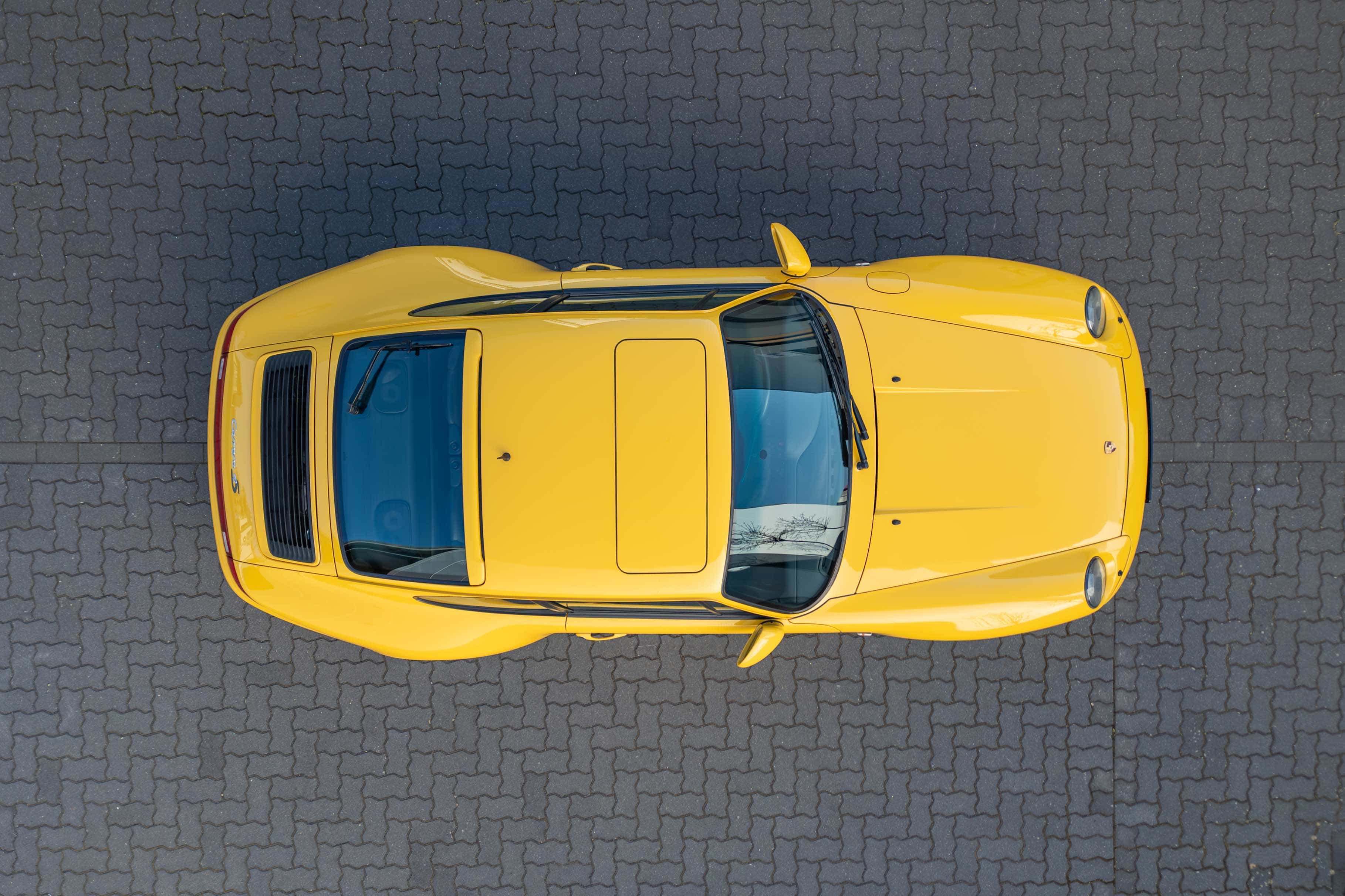 Porsche 993 Carrera 4S in Speedgelb – seltener Widebody-911 mit Turbo-Karosserie, Allradantrieb und 285 PS, fotografiert aus der Vogelperspektive.